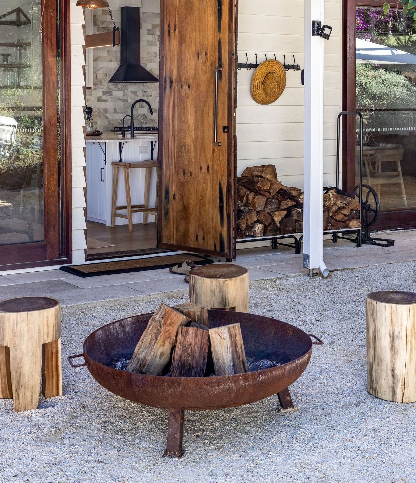 A fire pit with logs in it sits in front of a kitchen