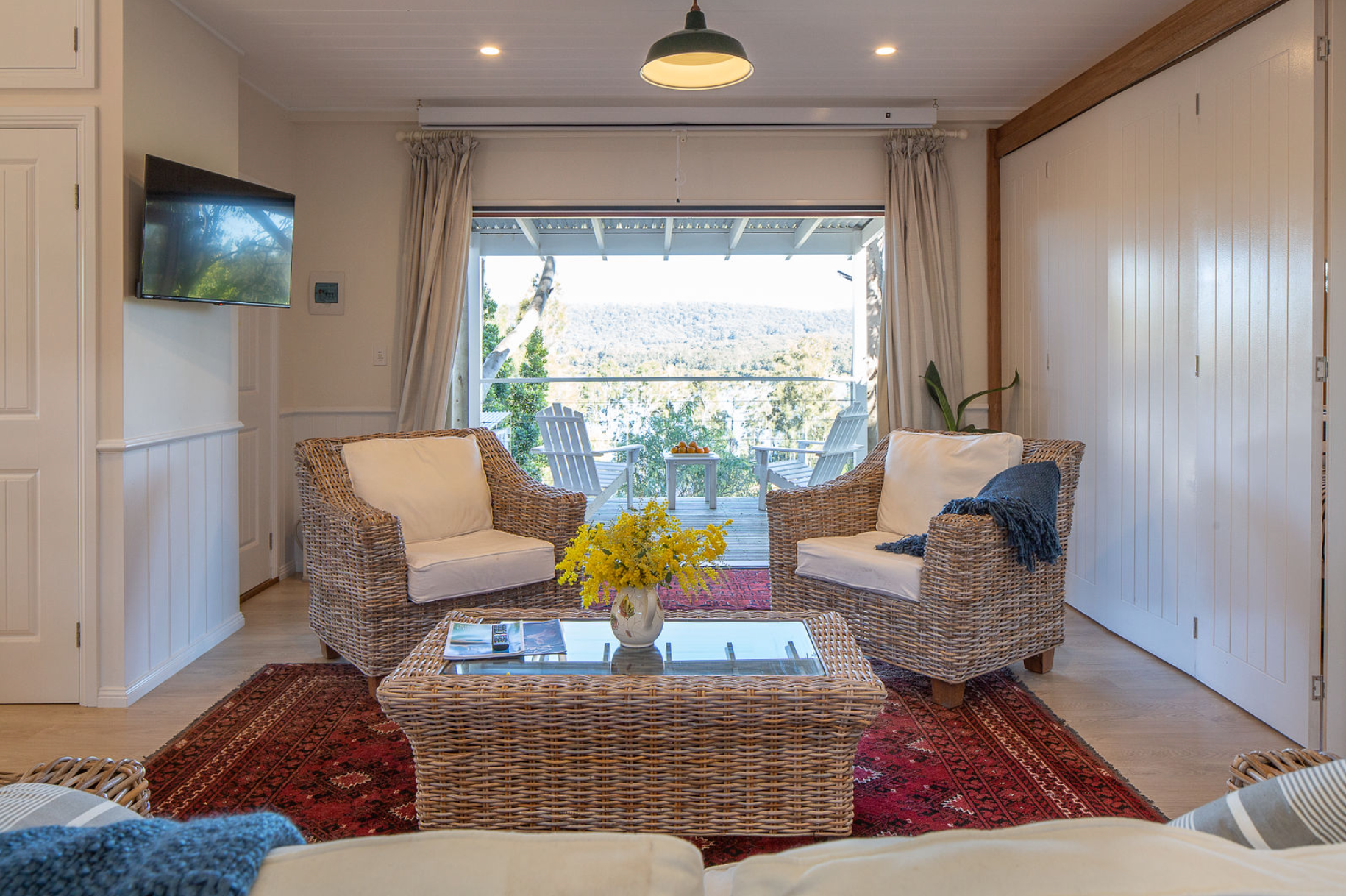 A living room with a couch , two chairs , a coffee table and a television.