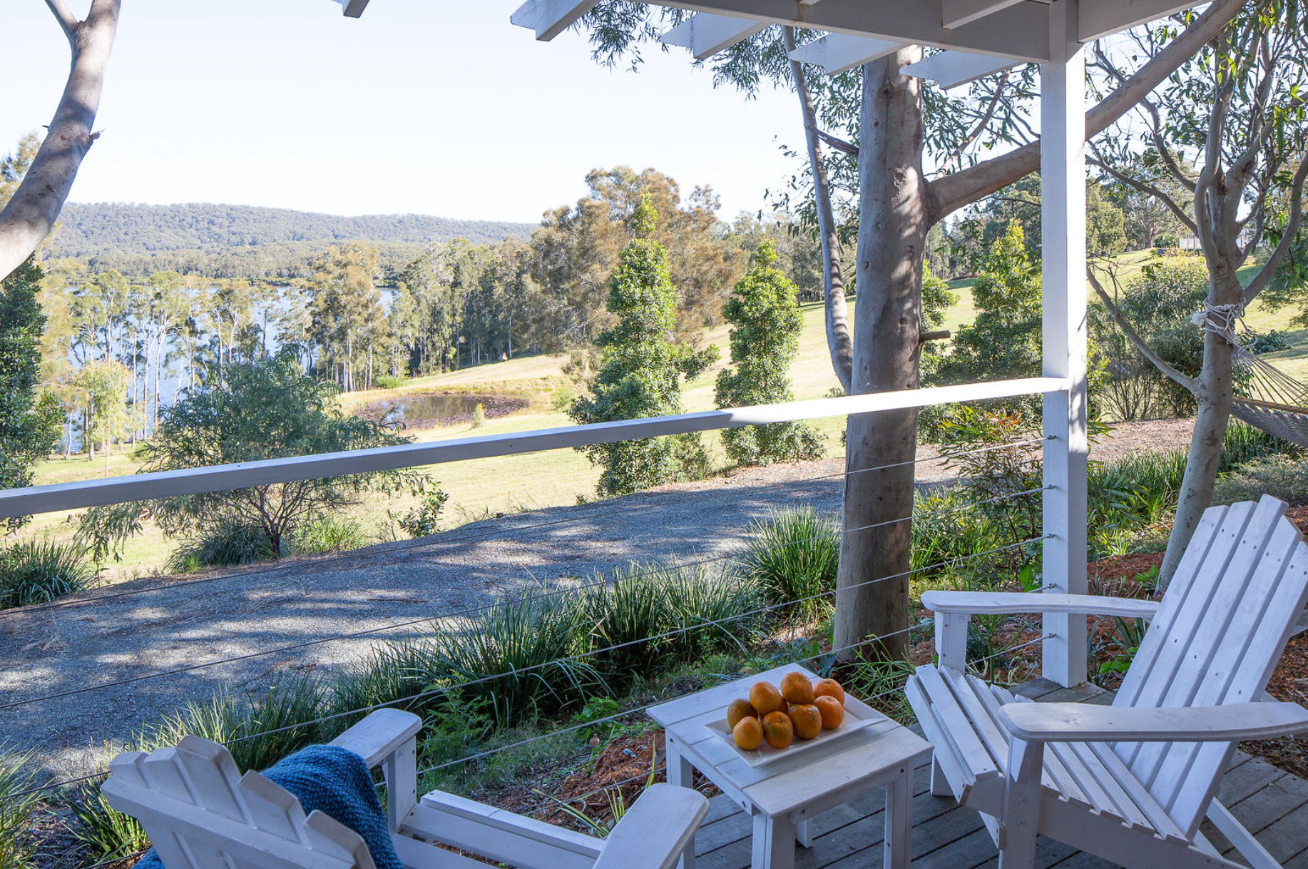 Two white chairs are sitting on a deck overlooking a lake.