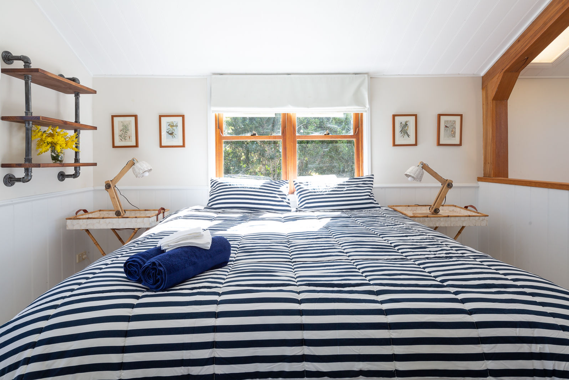 A bedroom with a bed , two nightstands and two windows.