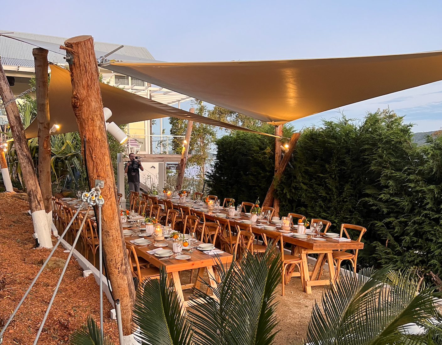 A long table and chairs under a canopy.