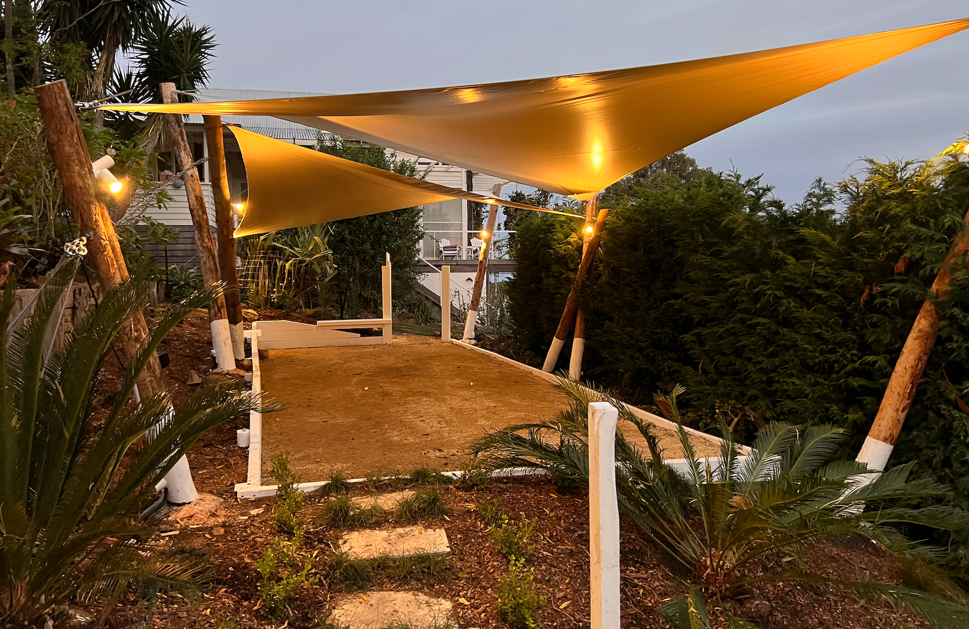 A canopy with lights on it is surrounded by trees and plants.