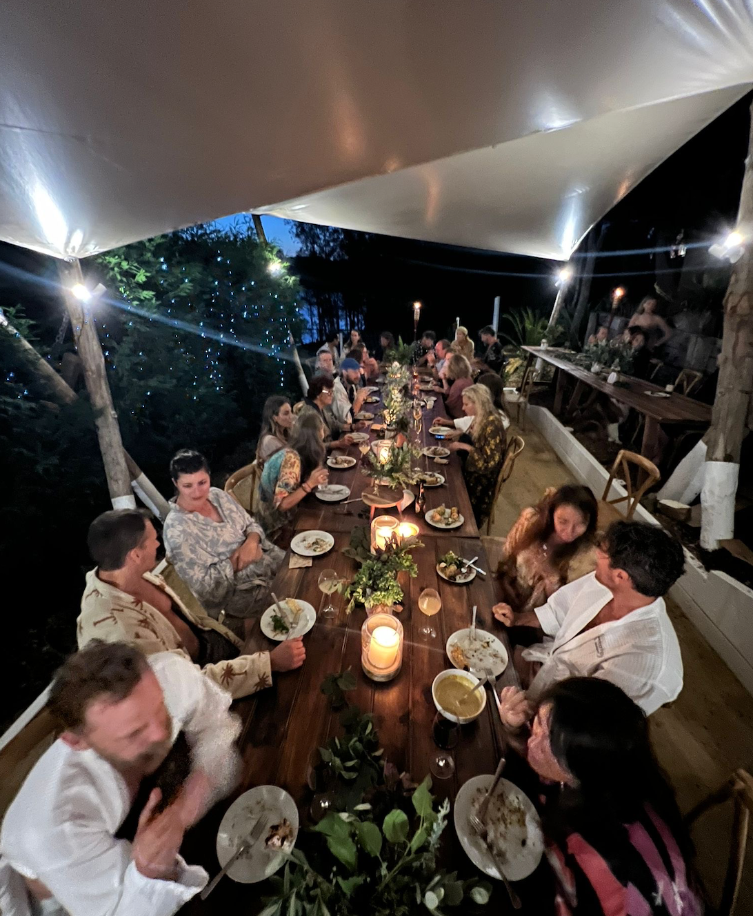 A group of people are sitting at a long table eating food.