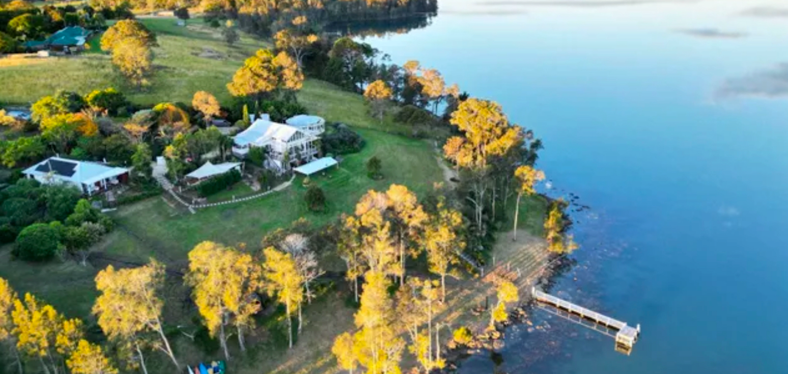 An aerial view of a lake with a dock and trees on the shore.