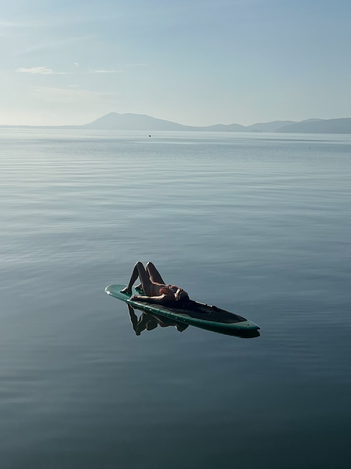 A person is laying on a surfboard in the middle of the ocean.