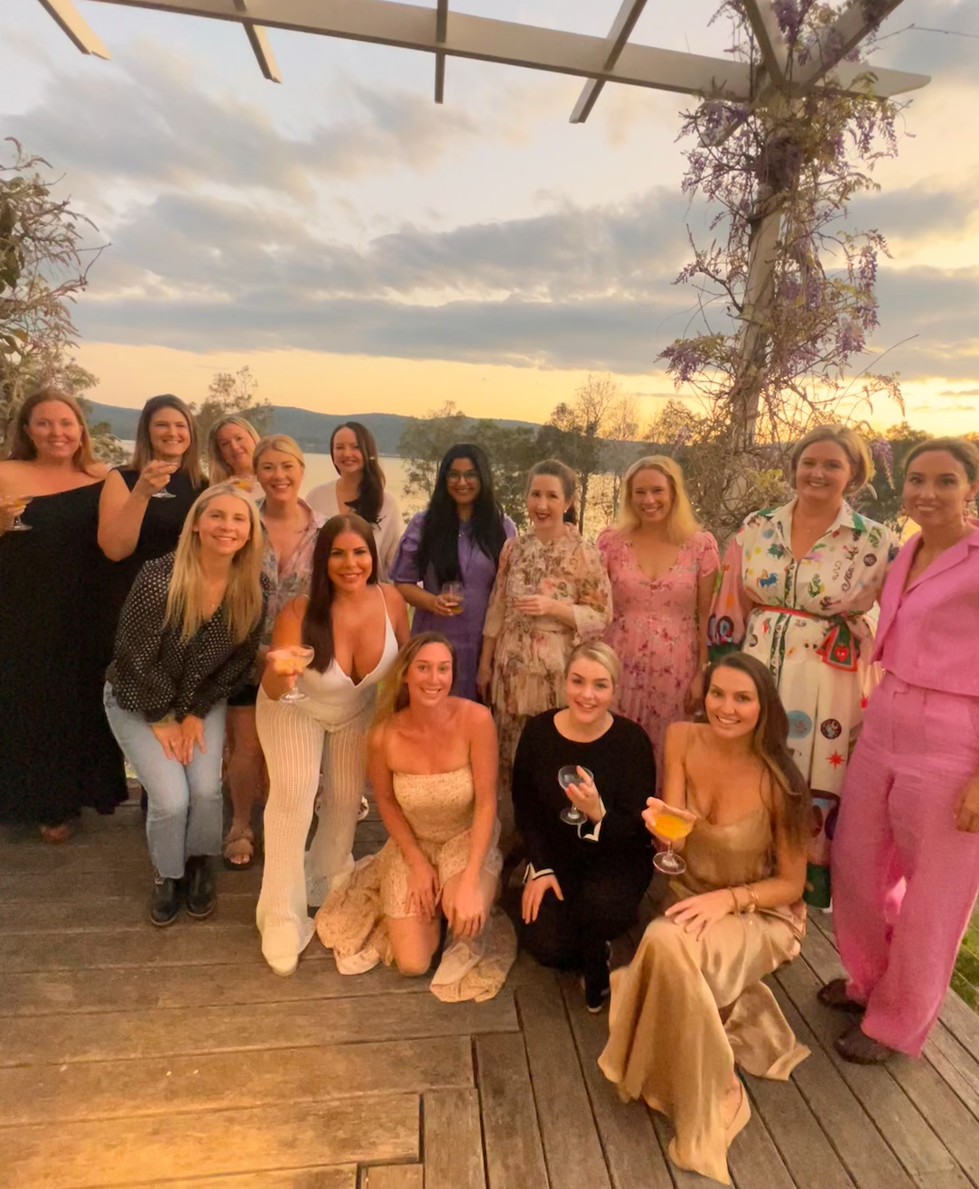 A group of women are posing for a picture on a wooden deck.