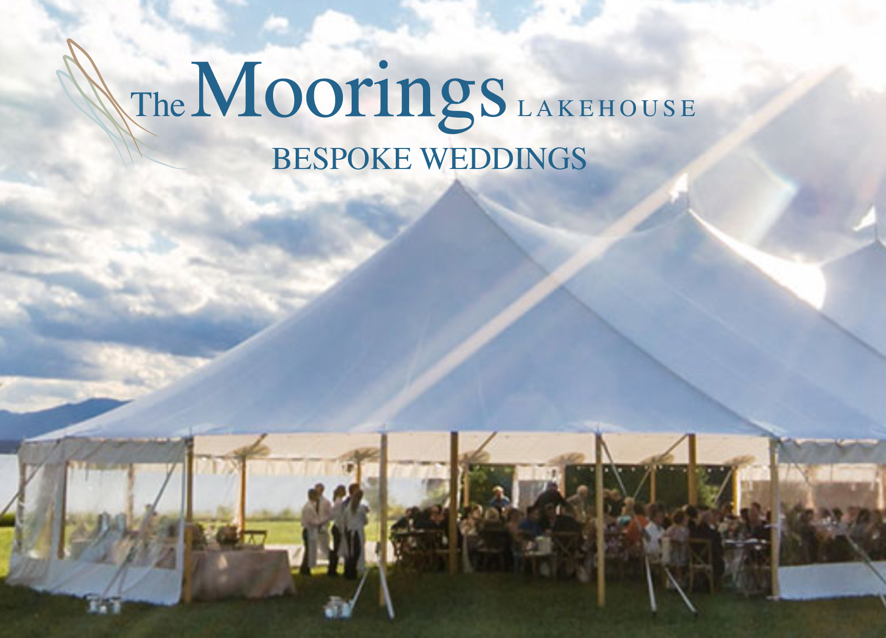 A large white tent with the words the moorings lakehouse bespoke weddings on it