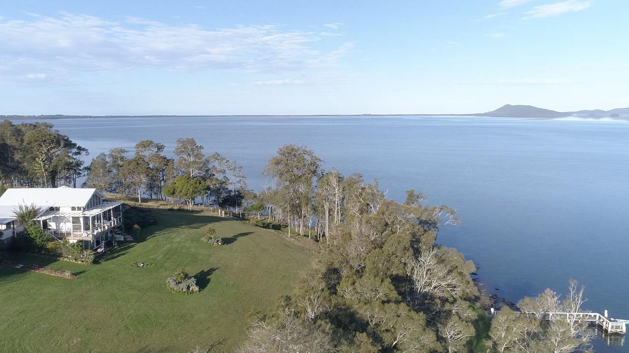 An aerial view of a house on the shore of a lake.
