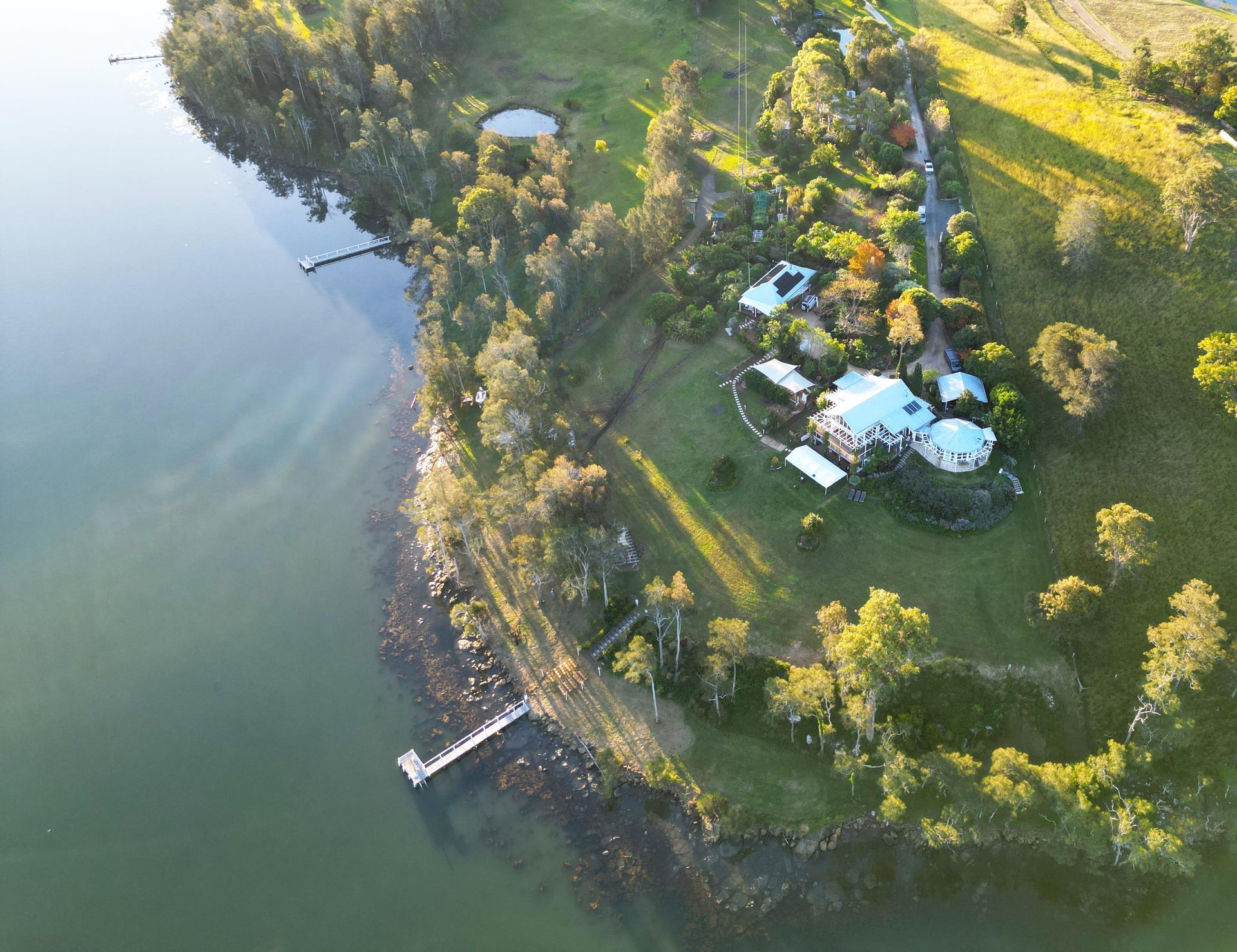 An aerial view of a house on the shore of a lake surrounded by trees.