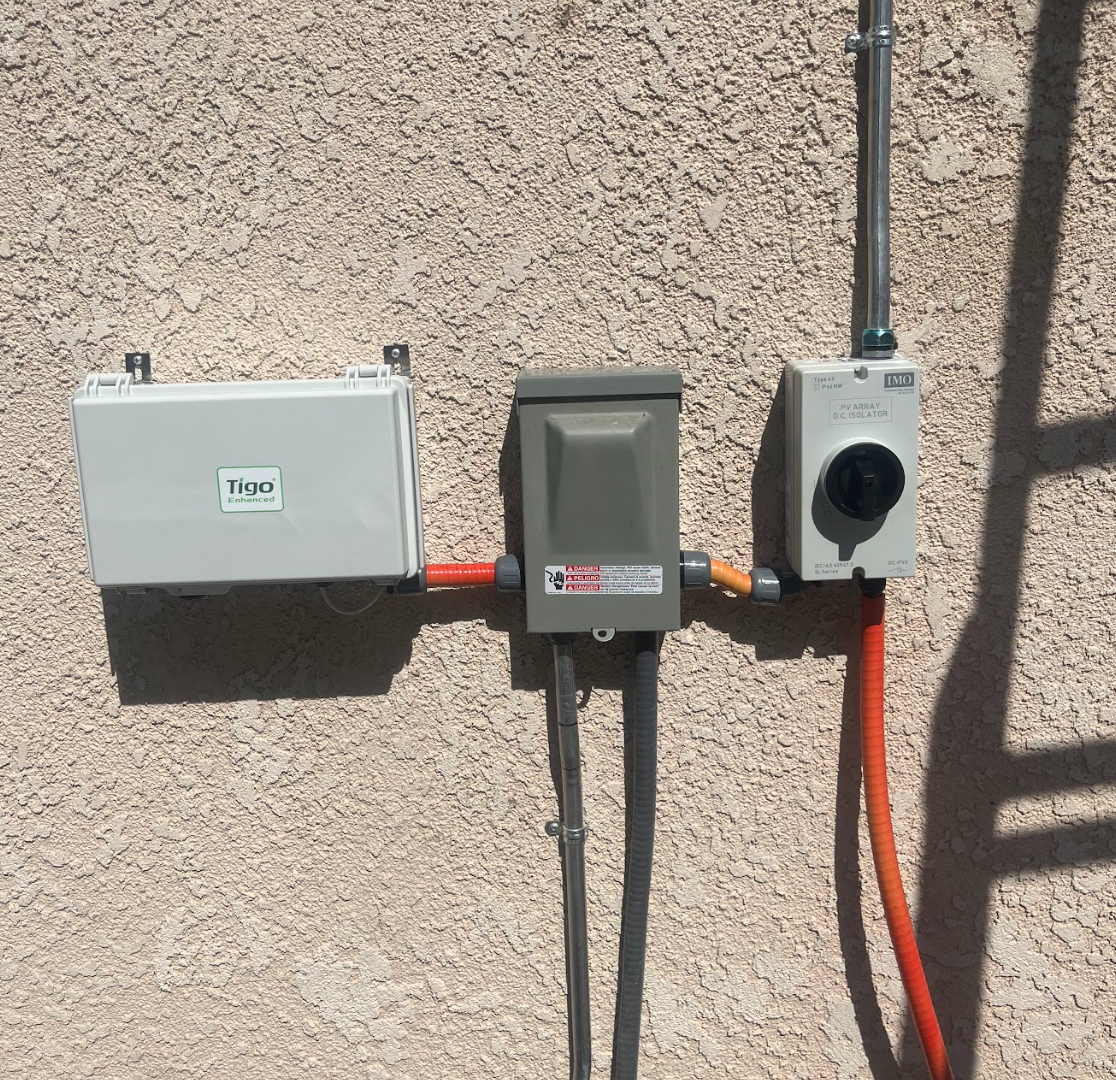 Four air conditioning condenser units sit on a concrete path against a brick wall.