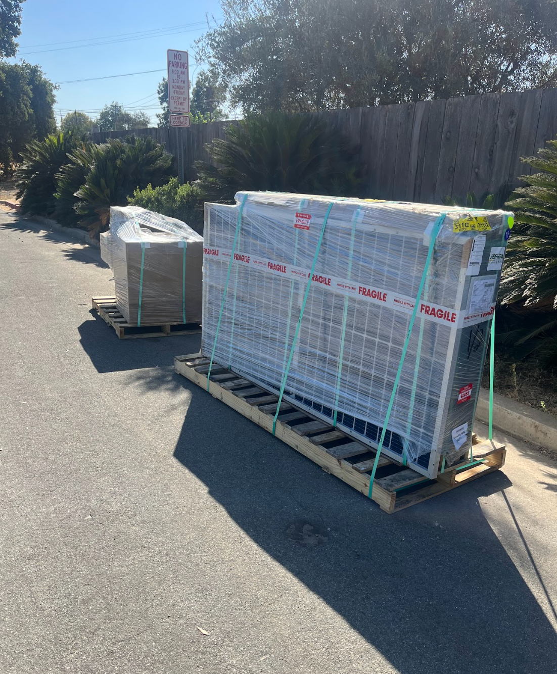A worker in grey workwear installs a solar panel on a rooftop, securing the frame with their hand.