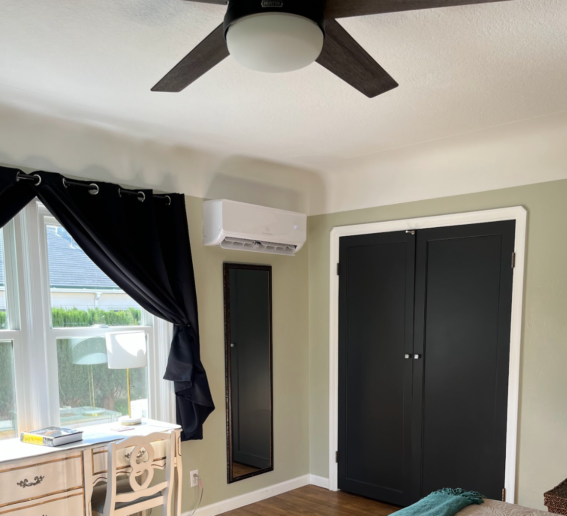Solar panels mounted on metal posts above a green utility box in a wooded area with red soil.