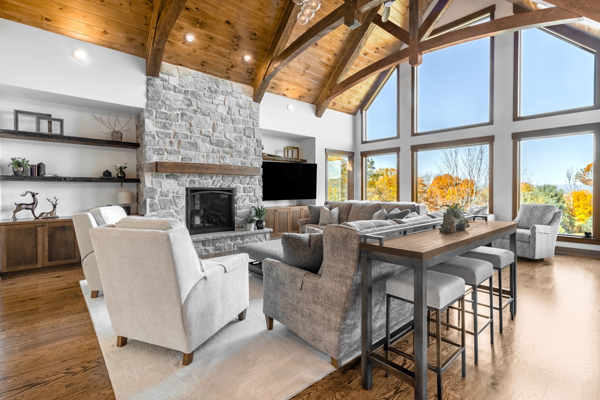 Amish home builder near me. Custom timber frame home in State College, PA. Living room with open concept, beams, stone fireplace.