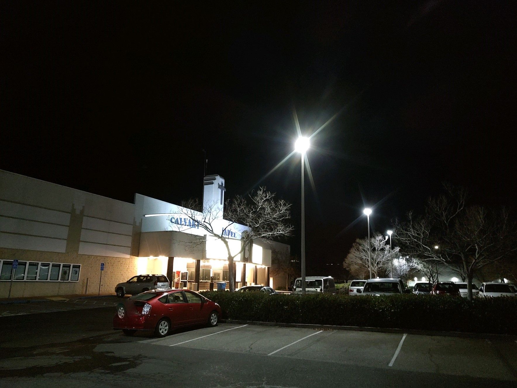 A red car is parked in front of a building at night