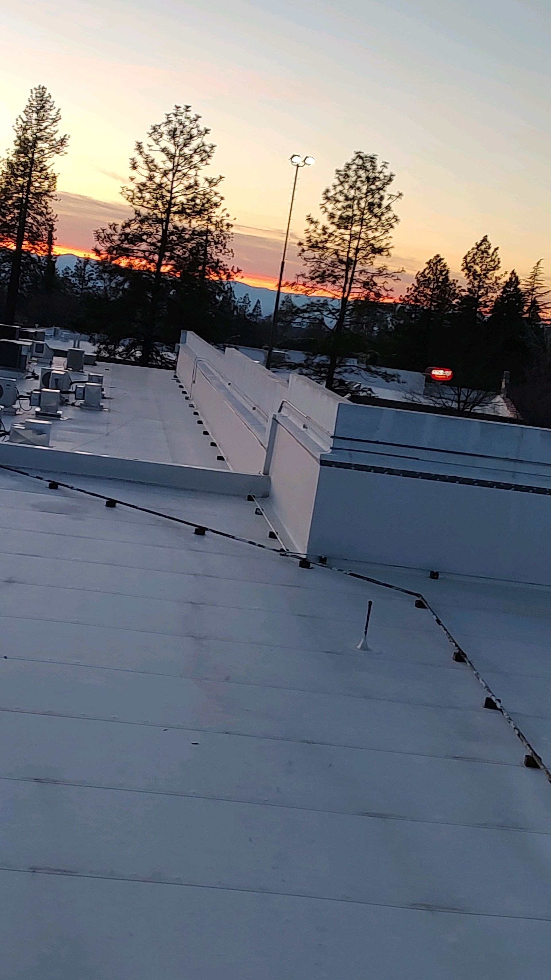 A snowy roof with a sunset in the background.