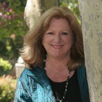 A woman with long brown hair is smiling for the camera.