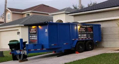 The logo'd dumpster for cleanup during roofing services by JBG Roofing in Kissimmee, FL