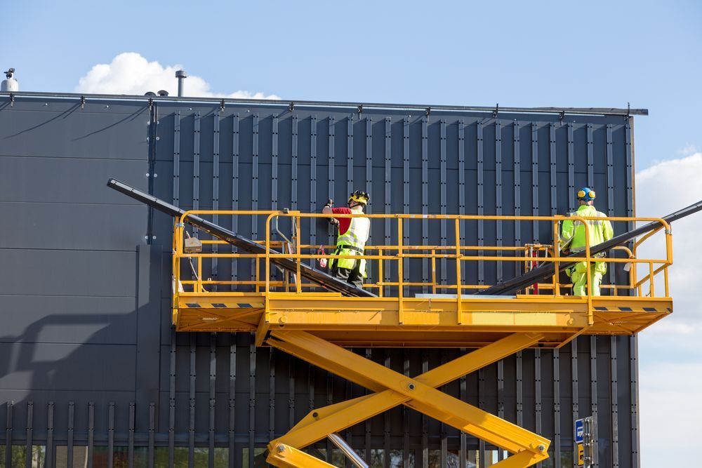 A Group of Construction Workers Are Working on The Side of A Building — PEPS Machinery Services In Logan, QLD