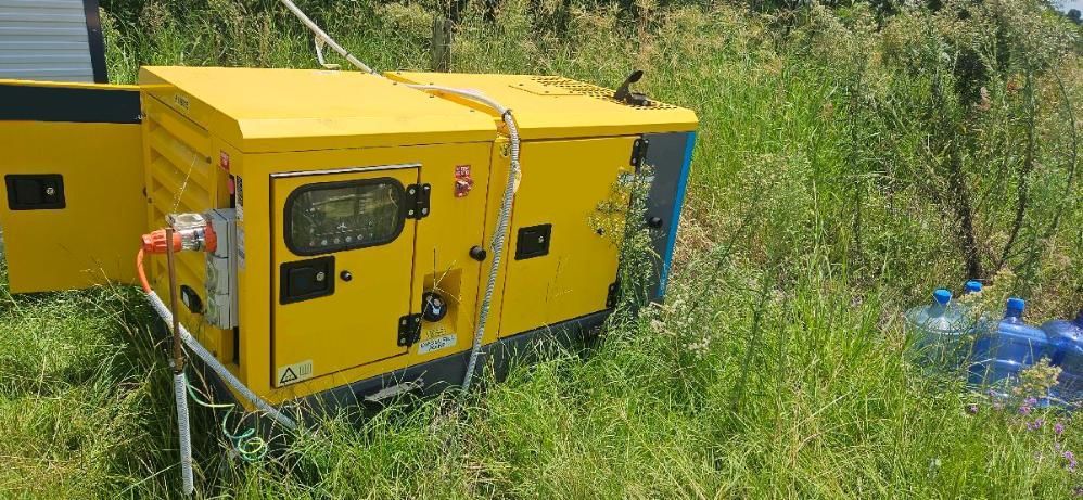 A Yellow Generator Is Sitting in The Middle of A Grassy Field — PEPS Machinery Services In Bethania, QLD