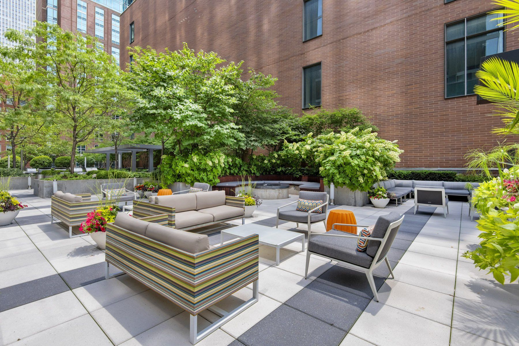A patio with a lot of furniture and trees in front of a brick building at State & Chestnut.