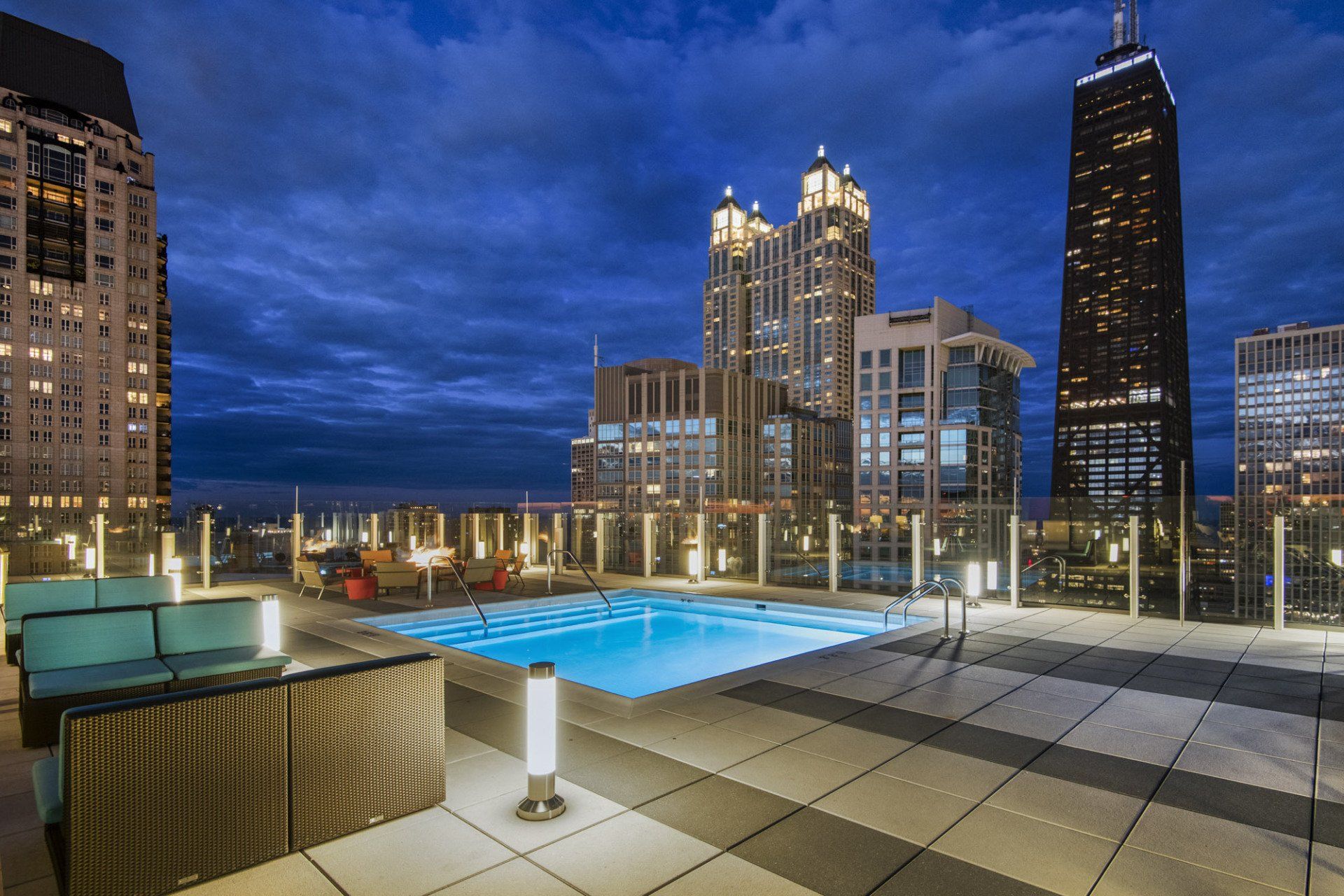 A swimming pool on a rooftop with a city skyline in the background at State & Chestnut.