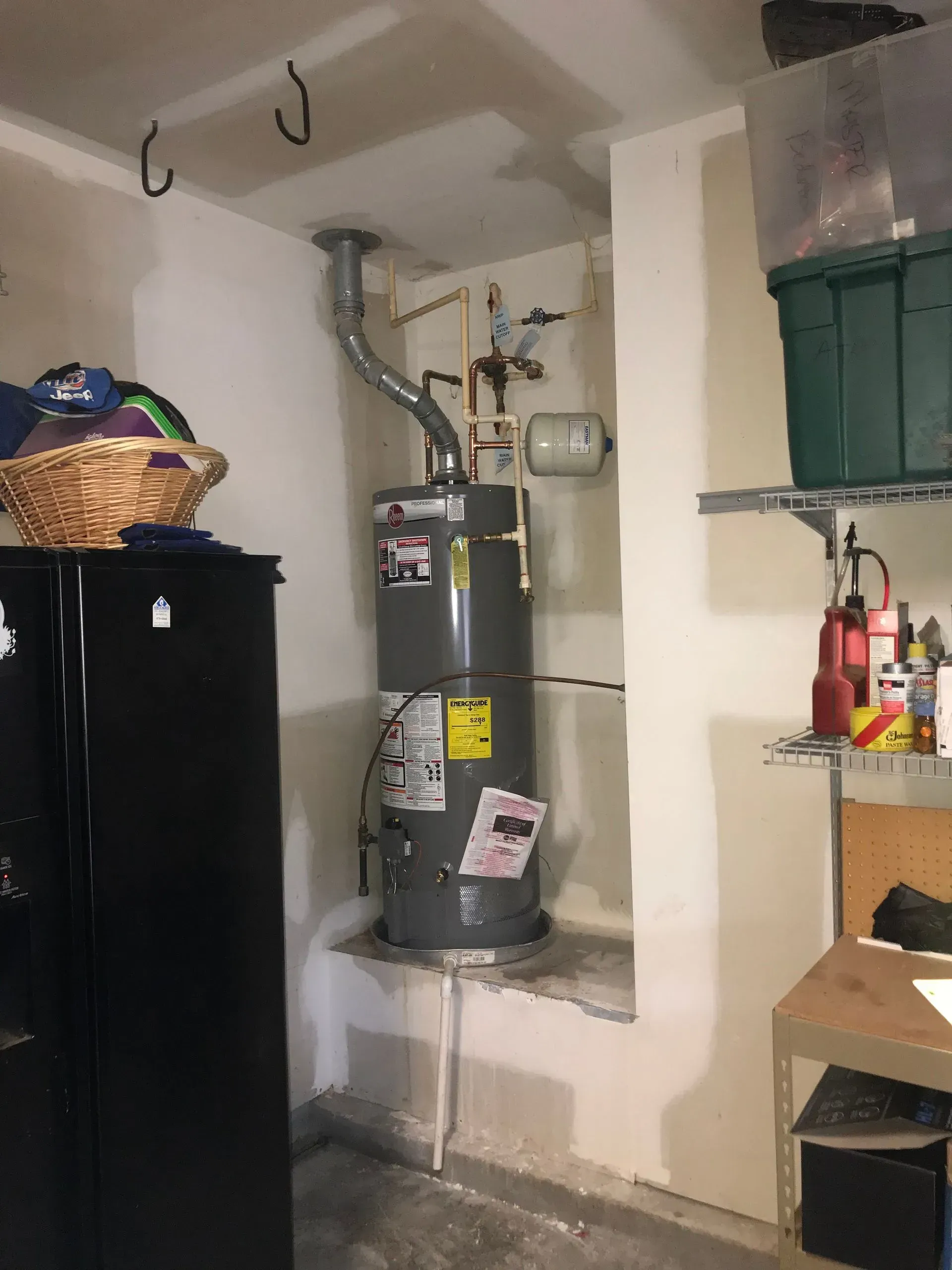 A water heater in a garage setting, positioned against a wall.