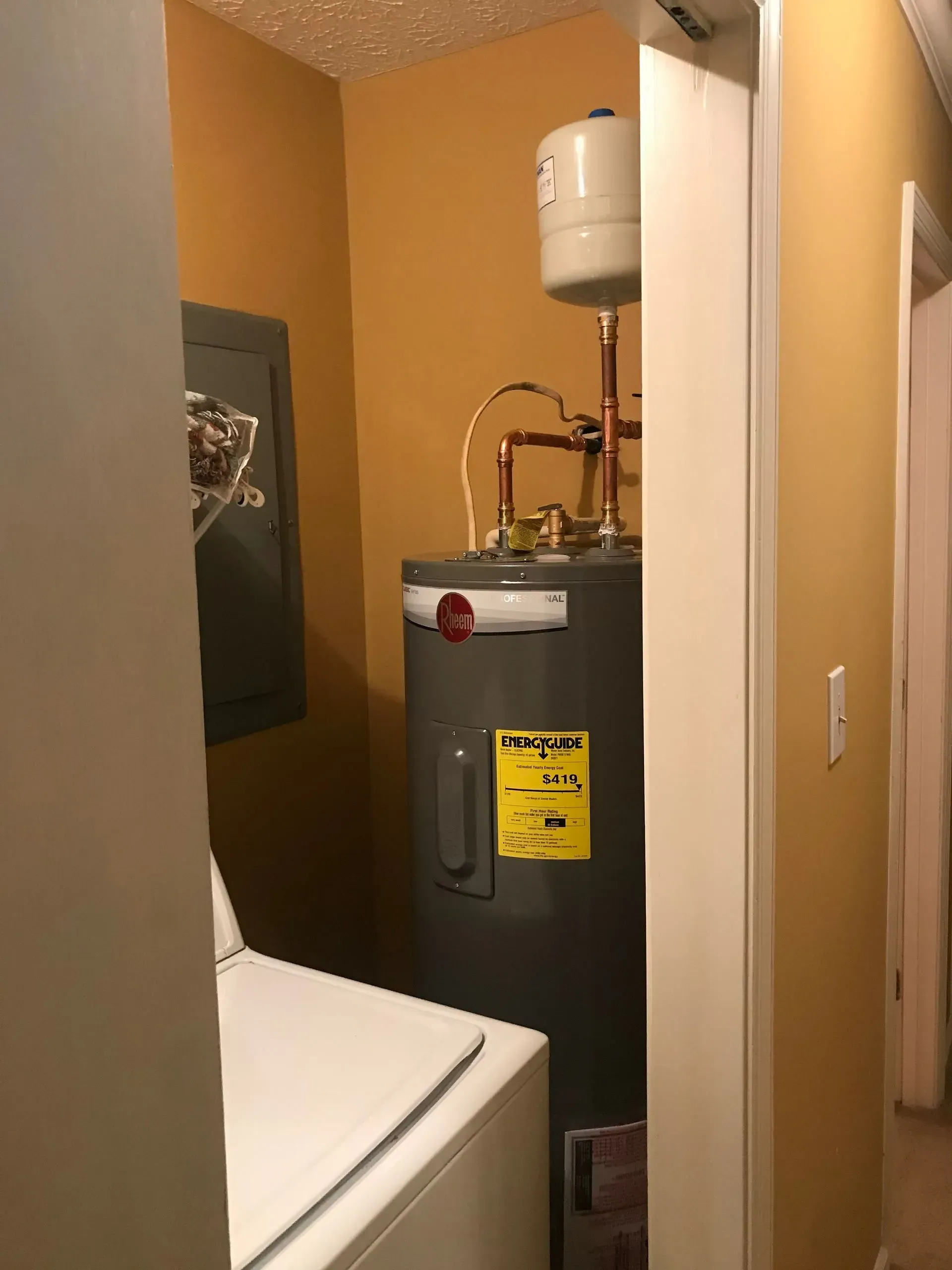 Laundry room with water heater, washing machine, and utility panel; walls are yellow.