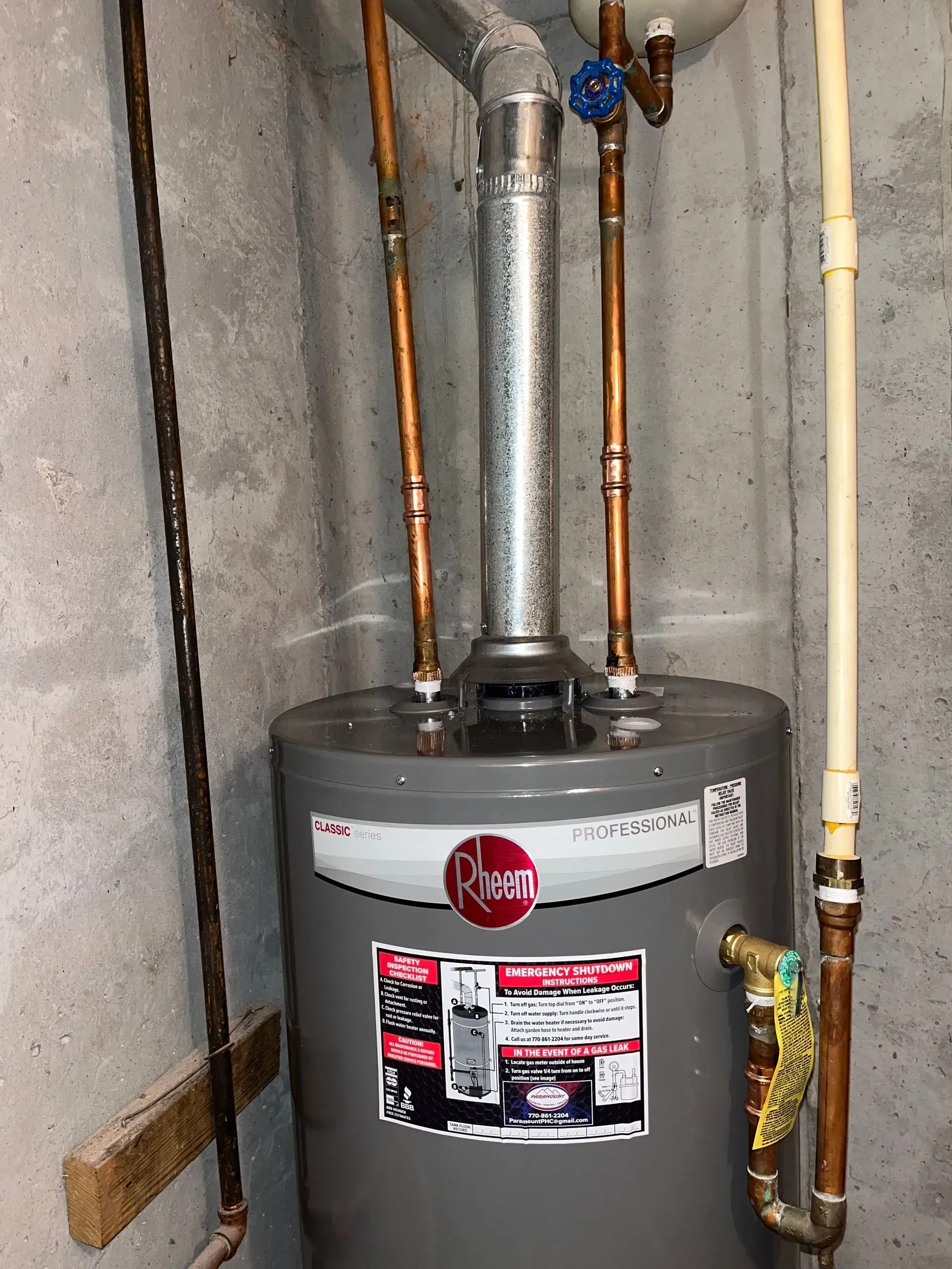 Rheem water heater in a basement, with copper pipes, a vent, and a yellow gas line.