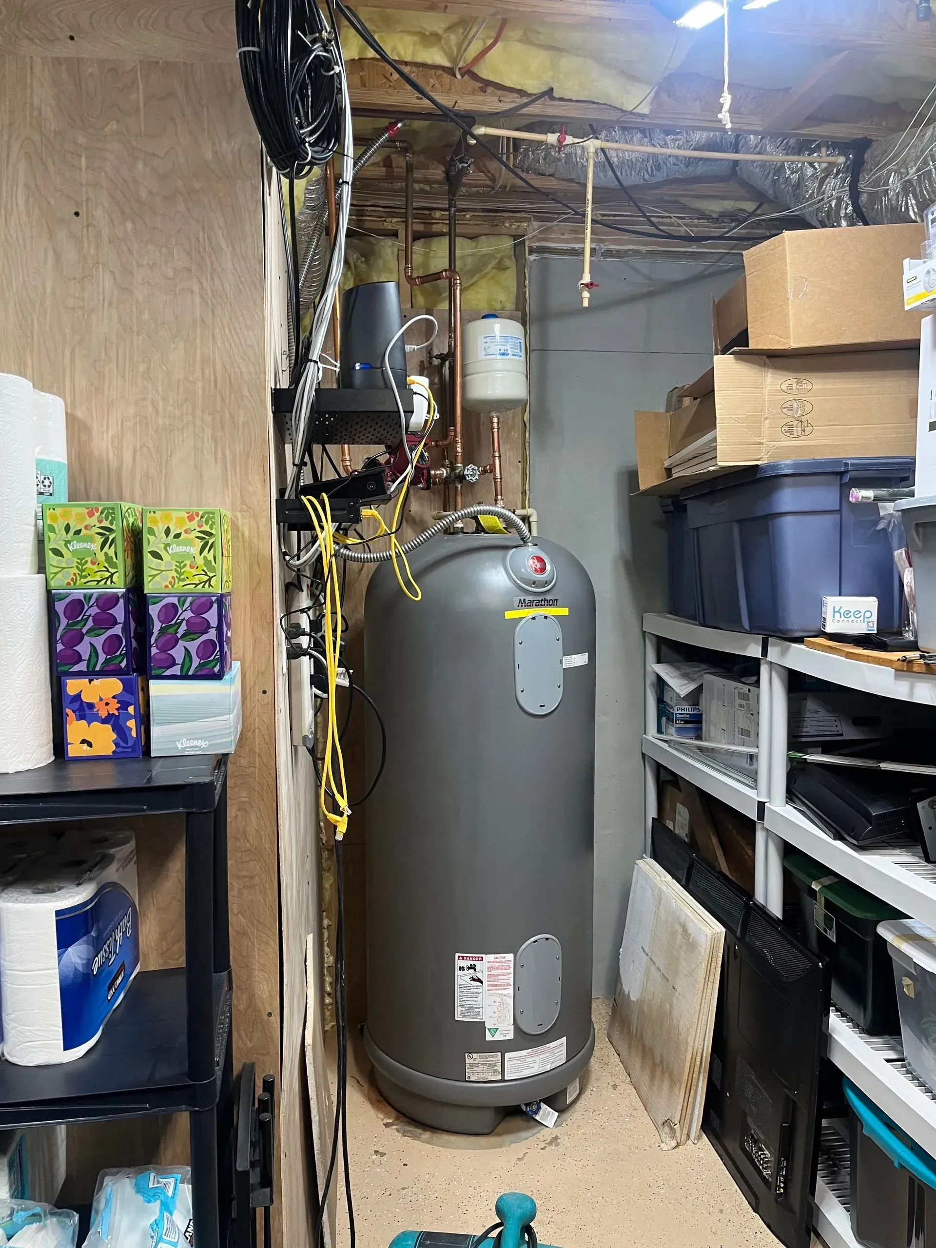 Basement with a gray water heater, storage shelves, and cardboard boxes.