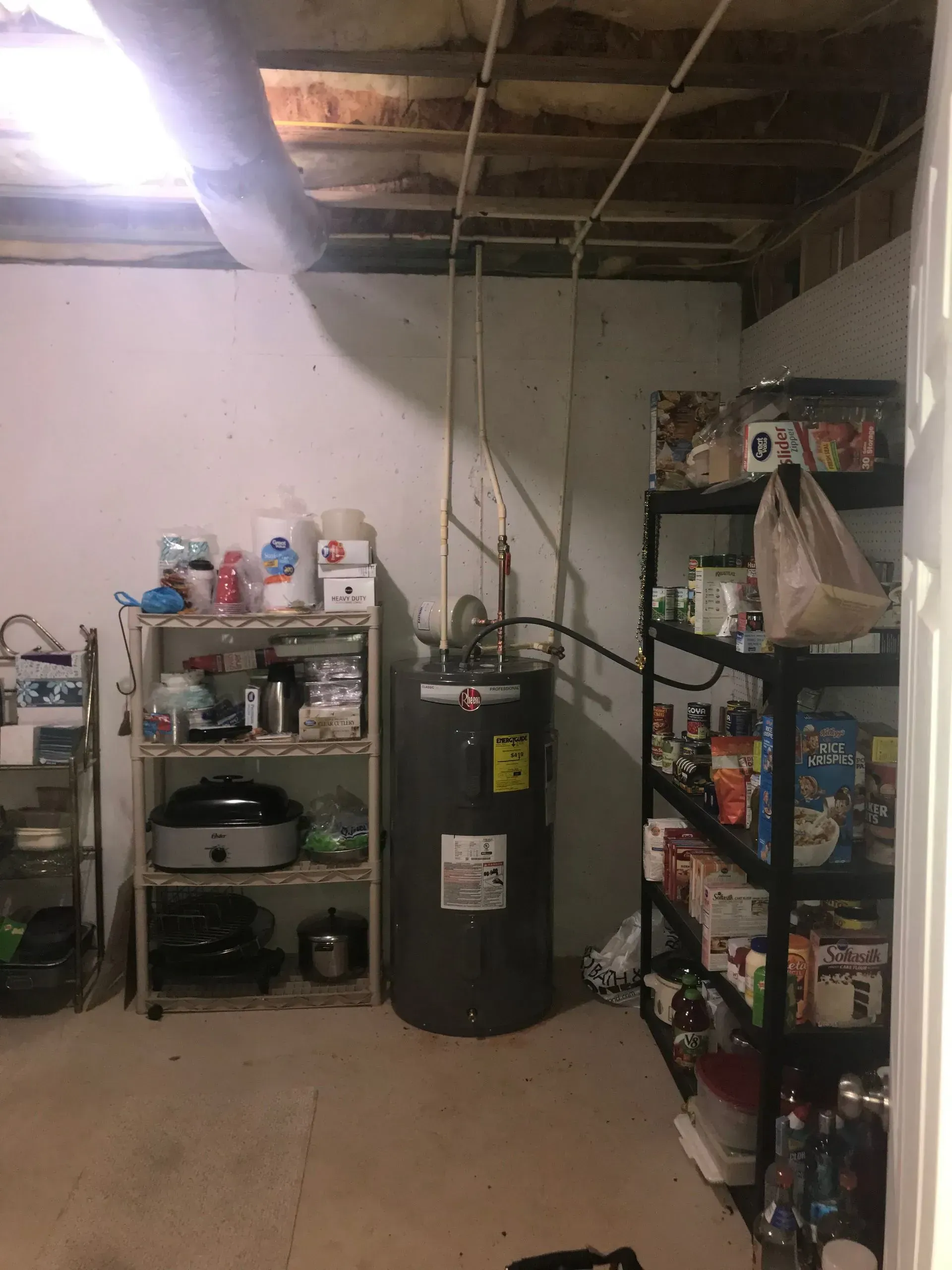 Basement storage area with water heater, shelves of food and household items.