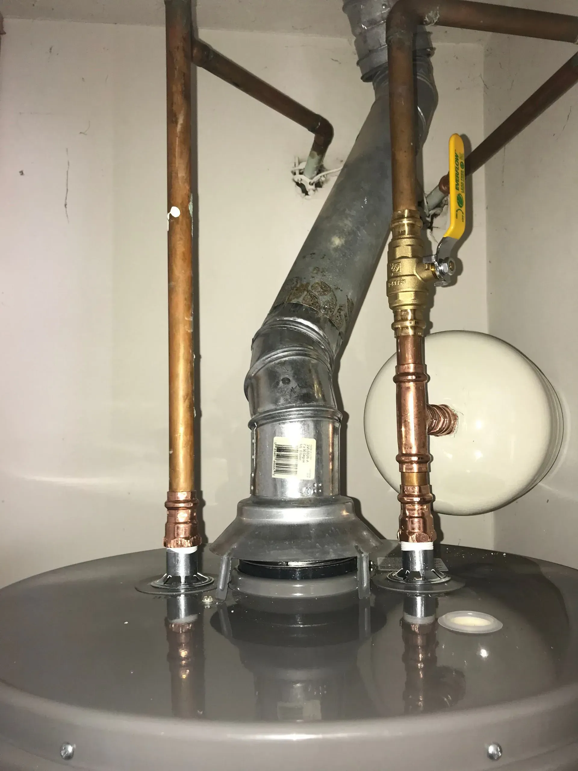 Water heater with copper pipes and a vent pipe.
