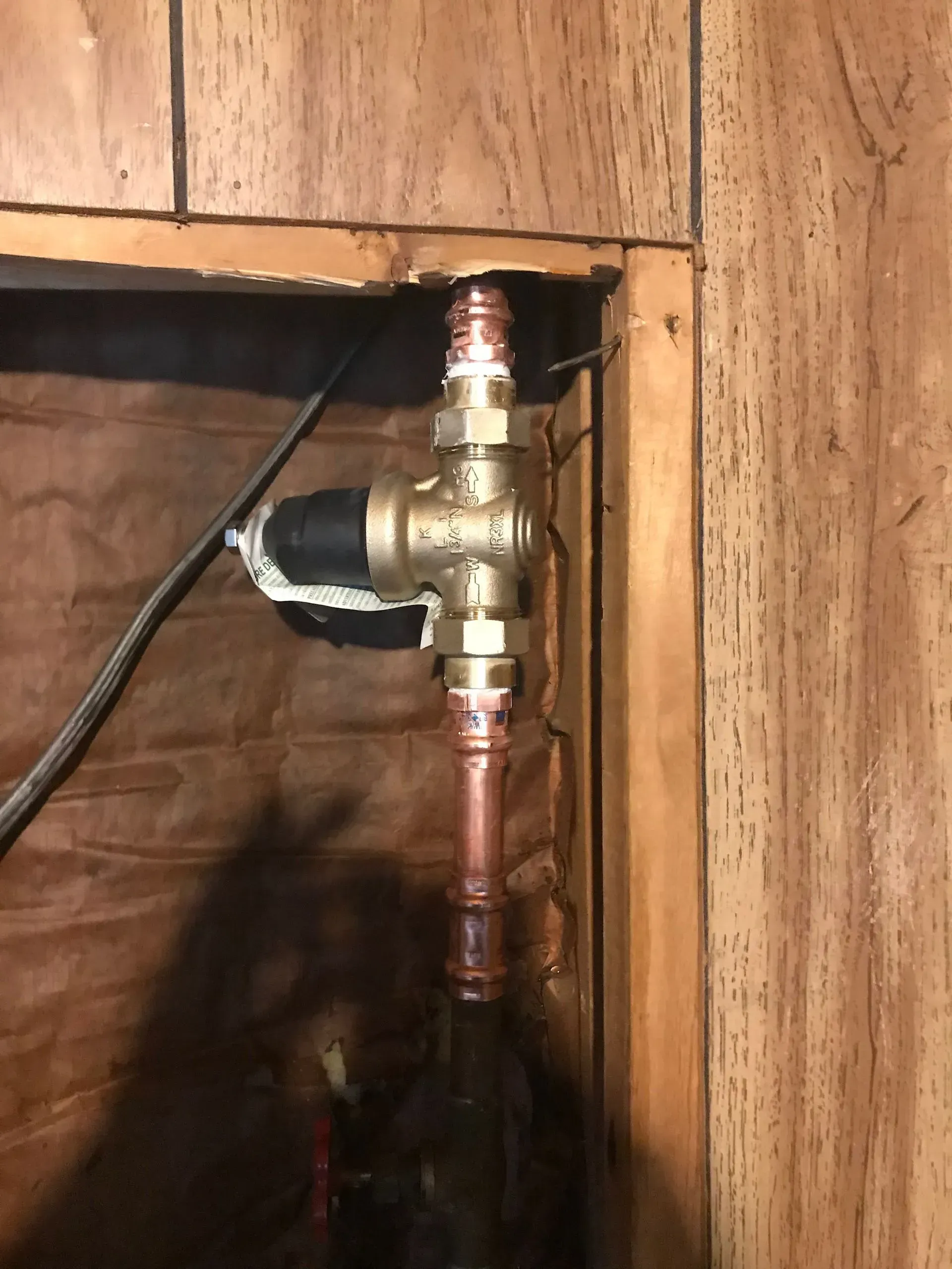Copper pipes and brass valve in a wooden wall cavity.