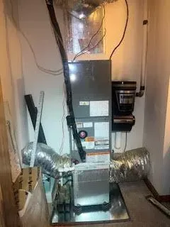 Furnace in a utility closet with ductwork and attached humidifier.