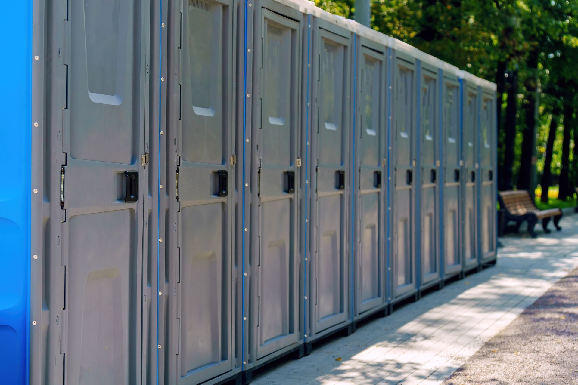 Row of brand new portable public toilets with the doors closed on a meadow.