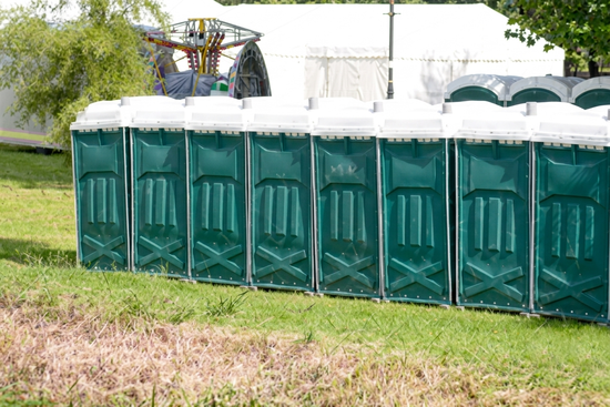 Row of green portable toilets at outdoor festival event on grass. Row of green portable toilets at outdoor festival event on grass.