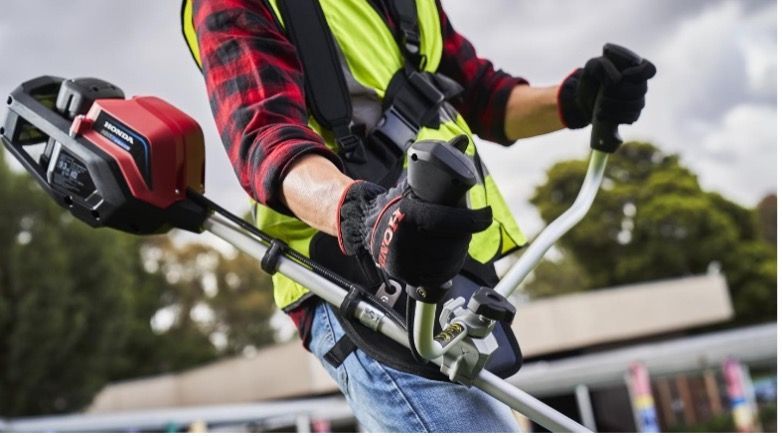 A man in a yellow vest is holding a lawn mower — Terrace Mowers in Raymond Terrace, NSW