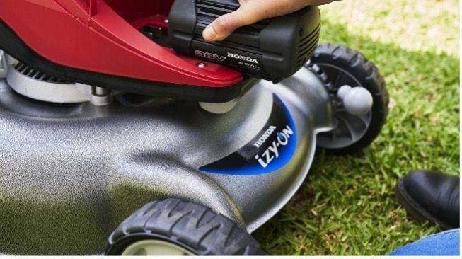 A person is inserting a battery into a lawn mower — Terrace Mowers in Raymond Terrace, NSW