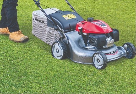 A person is using a Honda lawn mower on a lush green field — Terrace Mowers in Raymond Terrace, NSW