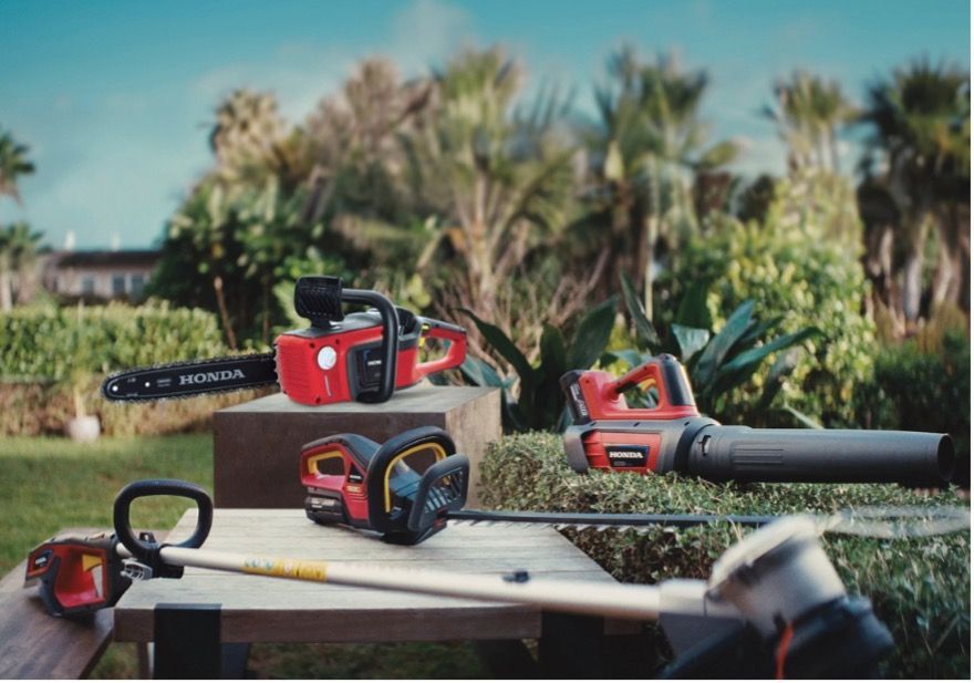 A chainsaw , trimmer , and blower are sitting on a wooden table  — Terrace Mowers in Raymond Terrace, NSW