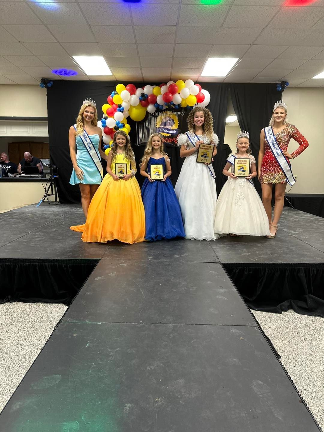 A group of women standing next to each other on a stage holding awards.