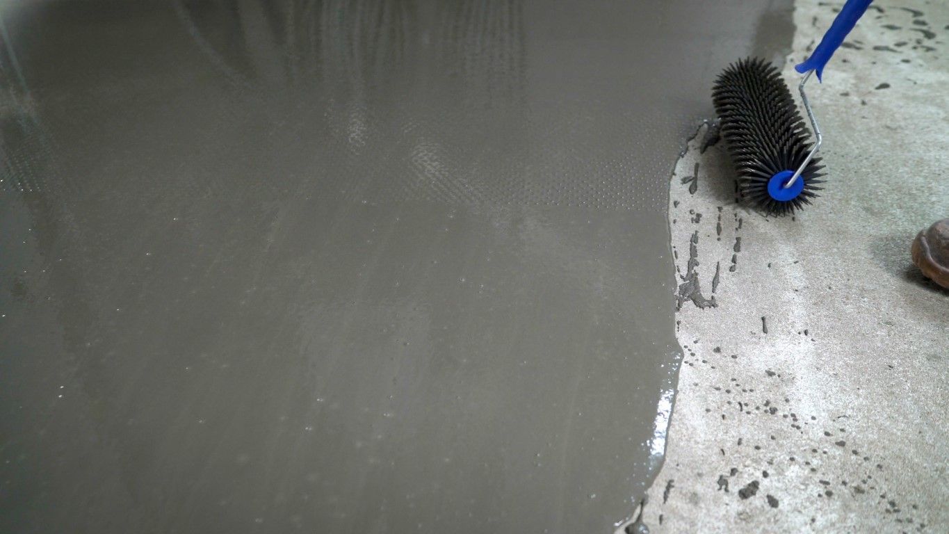 A person is cleaning a concrete floor with a brush.