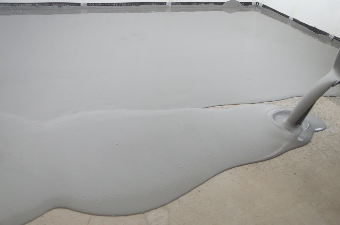 A gray liquid is being poured into a concrete floor.