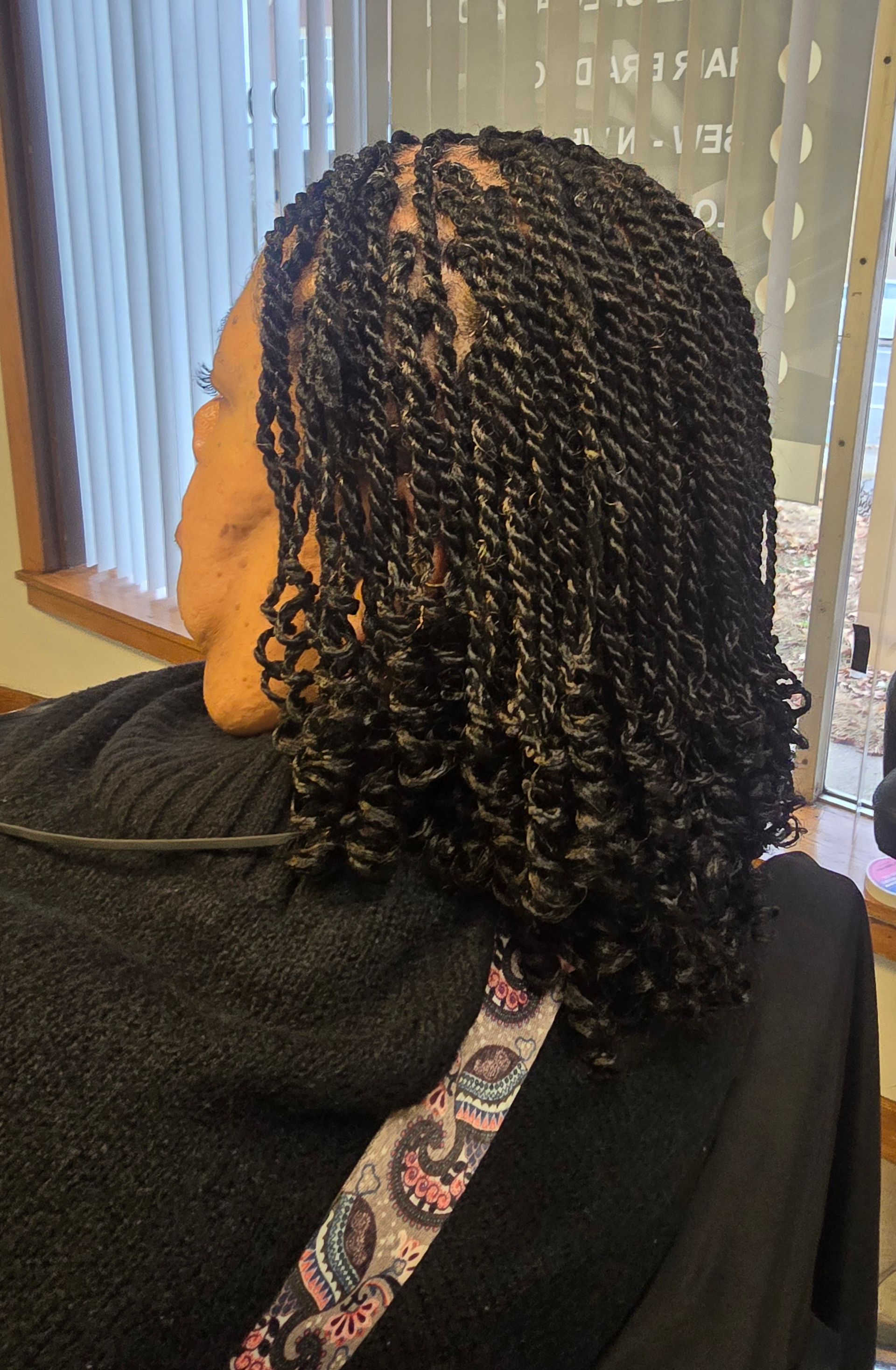 A woman with braids and curly hair is sitting in a chair.