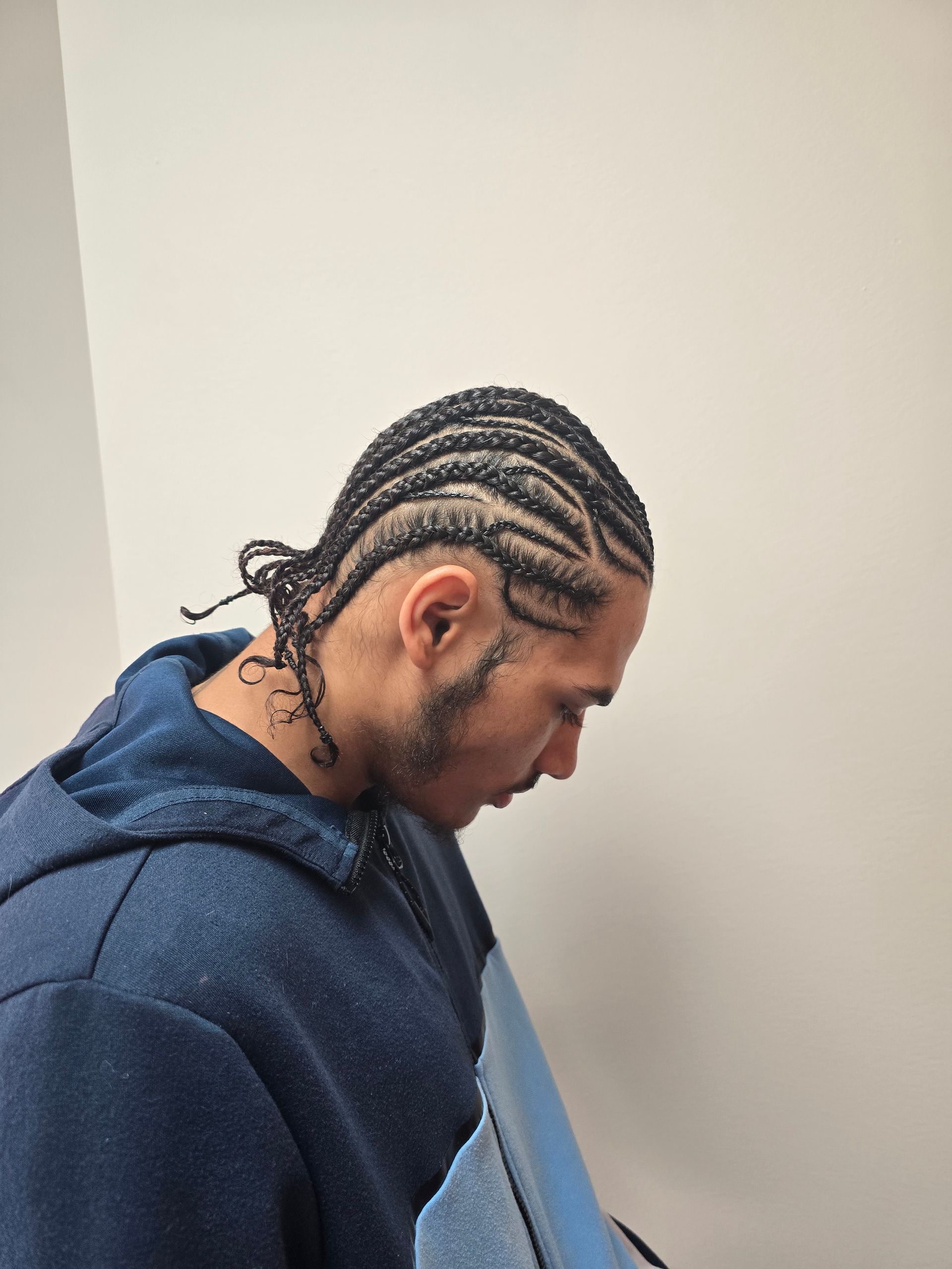 A man with braids on his head is wearing a blue hoodie.