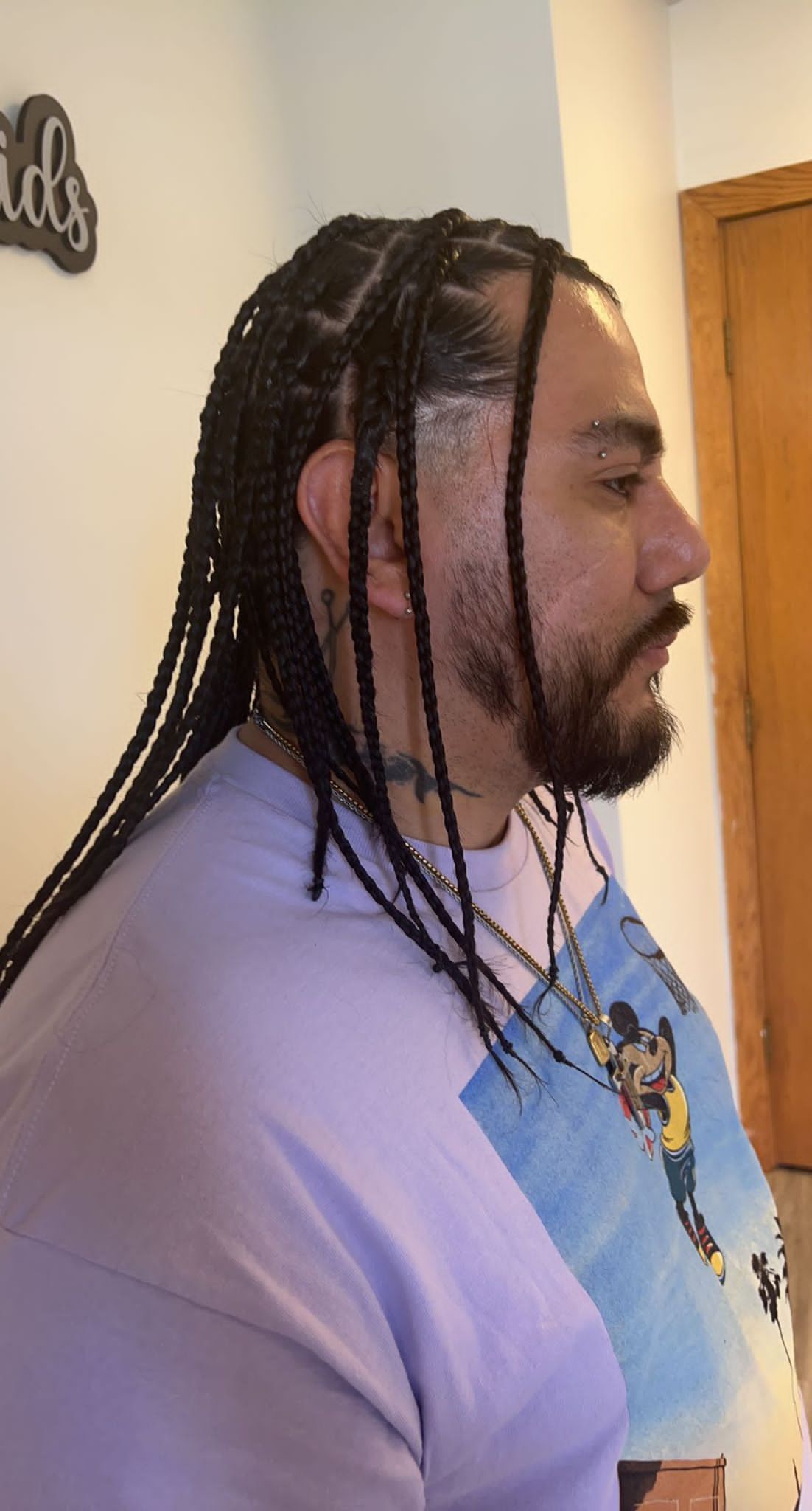 A man with dreadlocks and a beard is wearing a purple shirt.