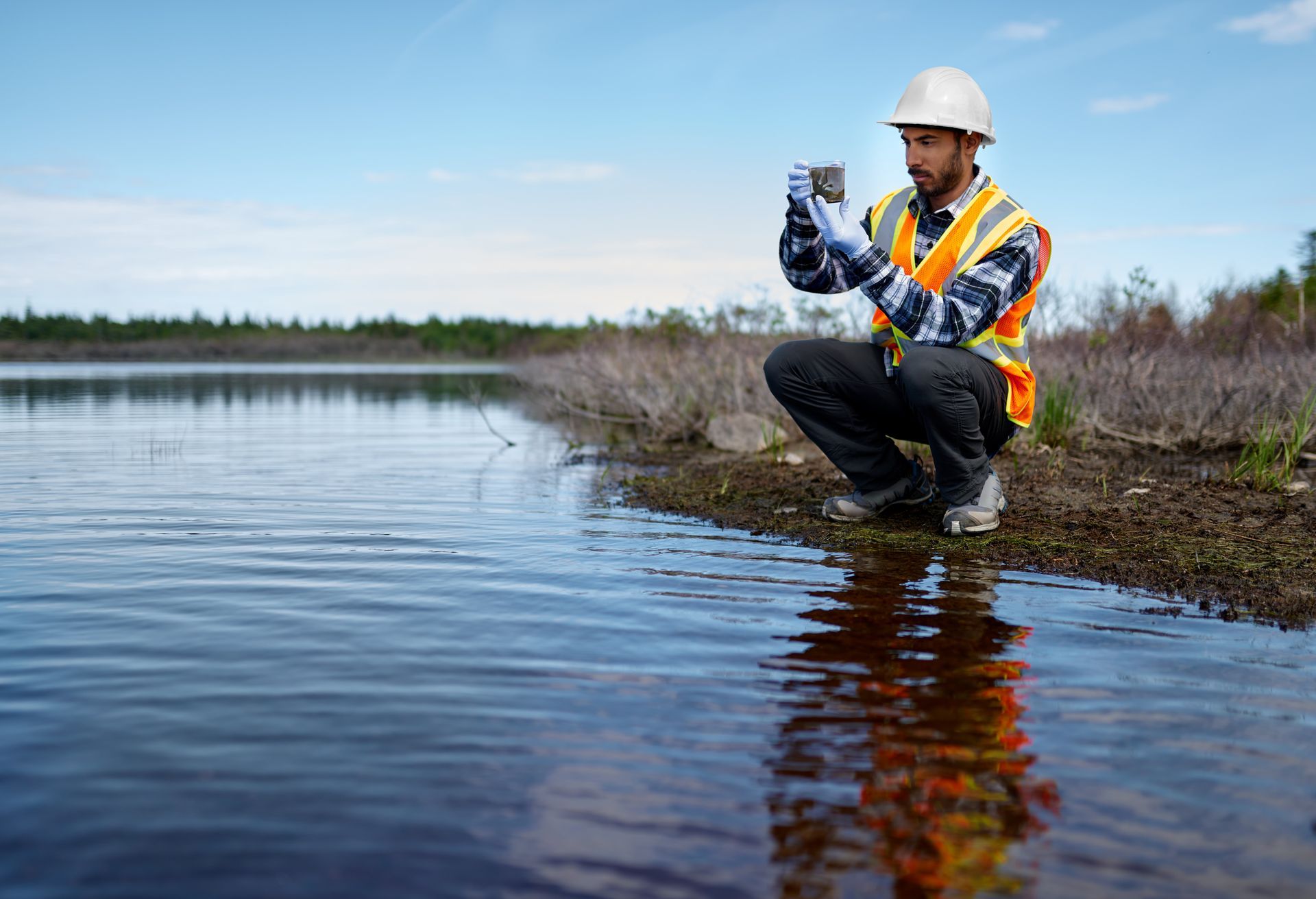 Technician collecting sample for surface water testing.