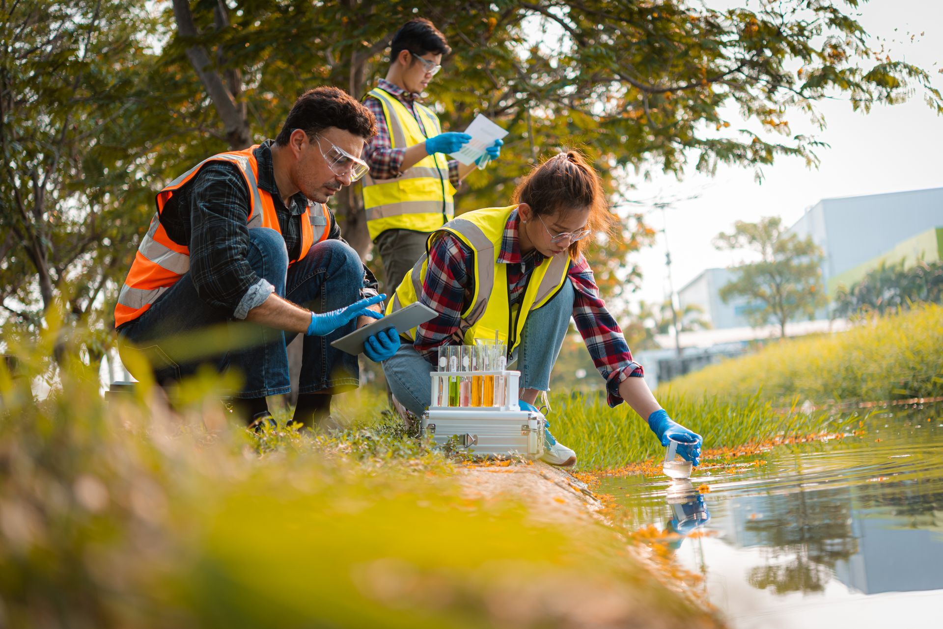 Environmental team conducting water quality testing at a stream using sampling bottles and tools. Environmental team conducting water quality testing at a stream using sampling bottles and tools.