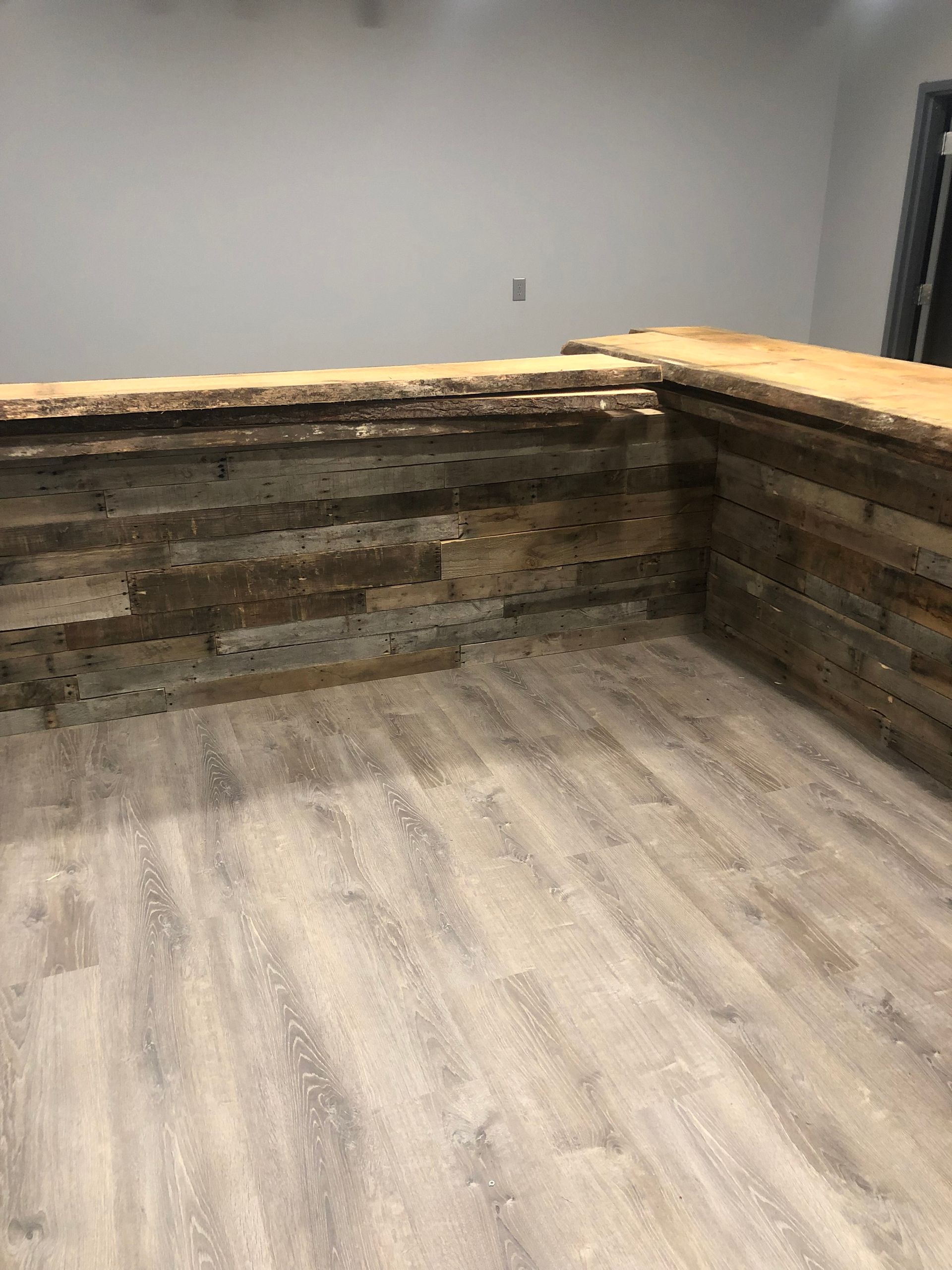 Wooden bar with light wood flooring in a room with white walls.