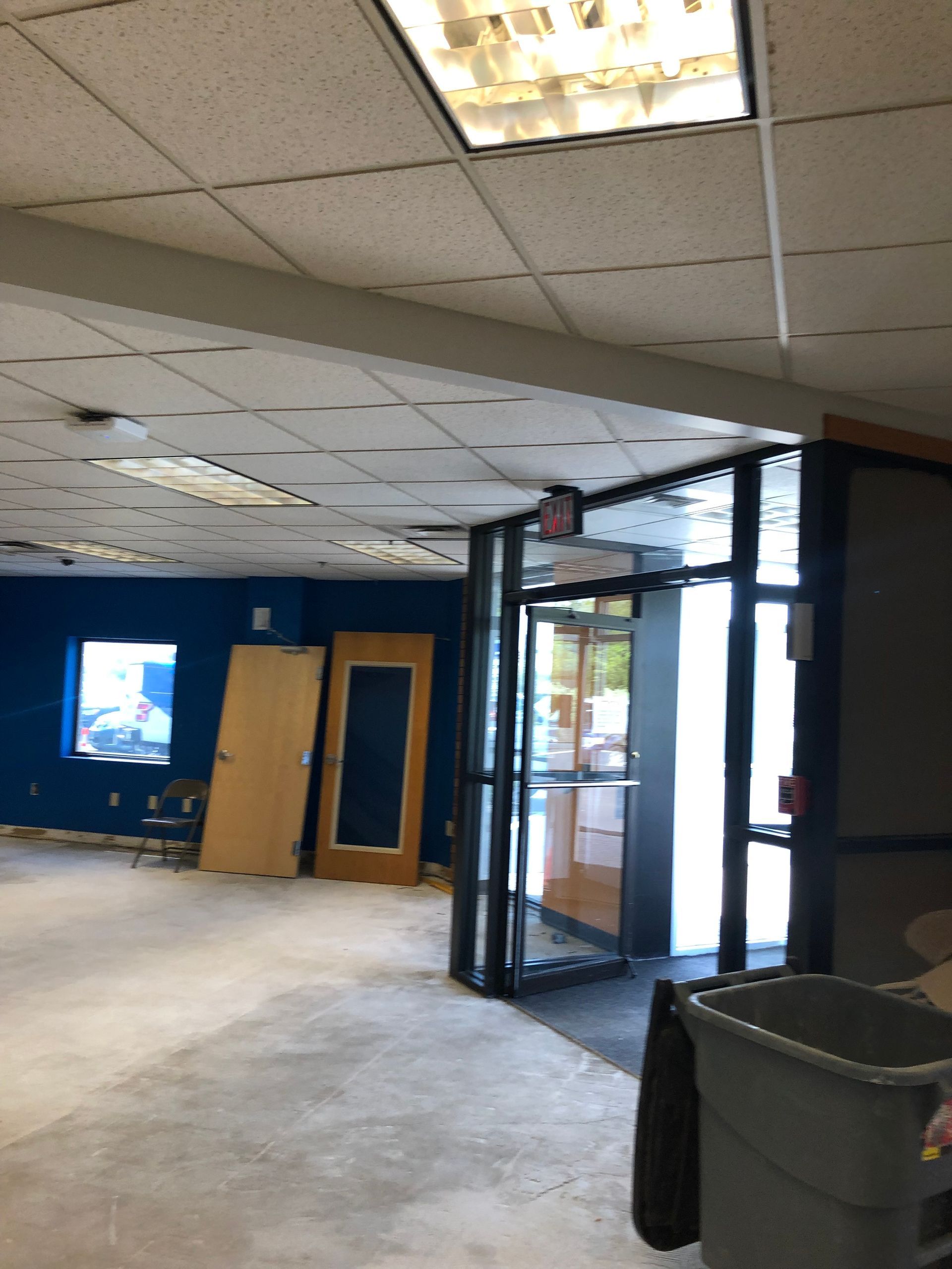 Interior view of a room with an entrance, unfinished walls, and two doors leaning against a blue wall.