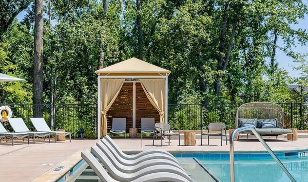 A swimming pool with a cabana and chairs around it.